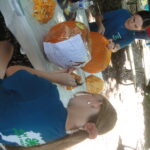 Two people trace a design on a pumpkin.