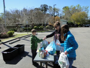 Food Drive donations being received by 4-H youth volunteer at the drive through drop-off event