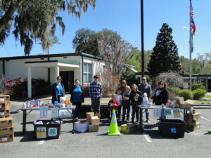 4-H parents and youth posing for a photo at a food drive drop-off location