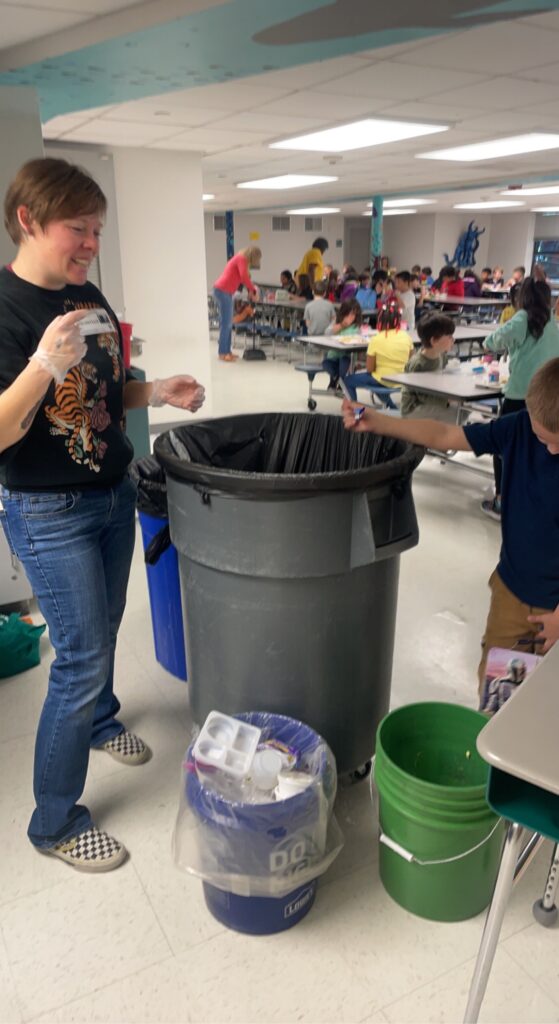 students separating recyclables and compostables from landfill items from lunch waste