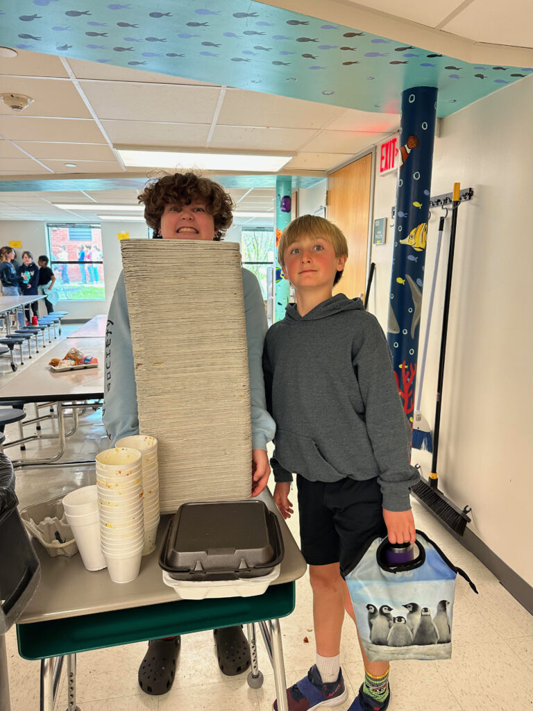 students and tall stack of compostable trays from lunch