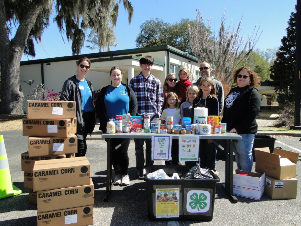 Food Drive donations being received by 4-H youth volunteer at the drive through drop-off event