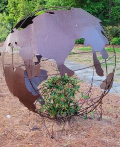 metal earth sculpture with green plant vine inside