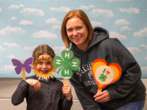 youth and adult smiling for a photo booth photo holding props