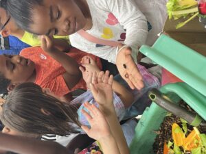 young student holding a worm in the palm of her hand