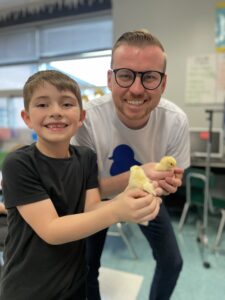 student and teacher holding a chick in the classroom