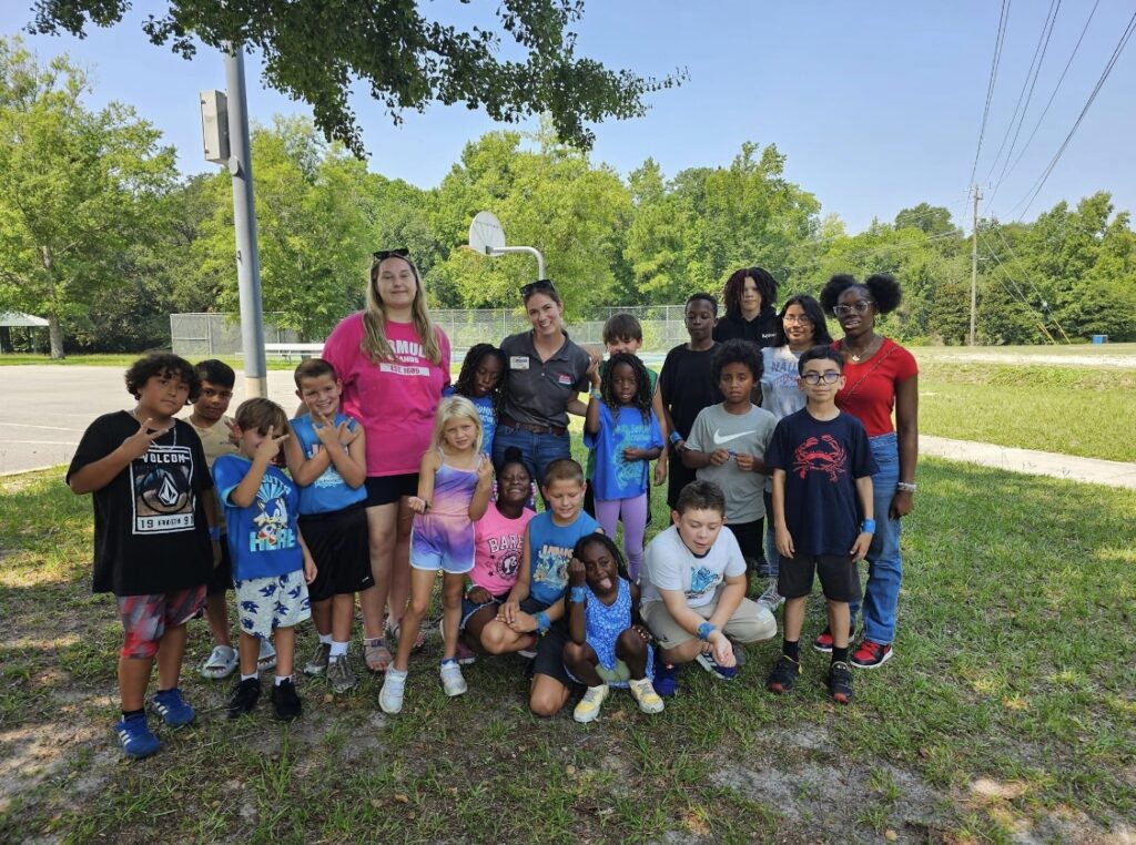 young students and teachers smiling for a photo outside